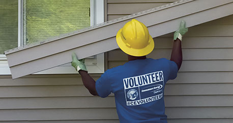 Consumers Energy volunteer putting siding on a home
